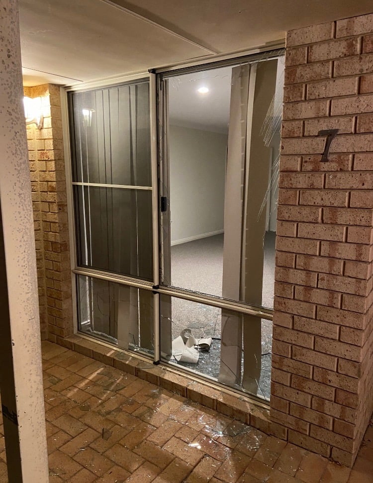 Broken window beside a front door with shattered glass