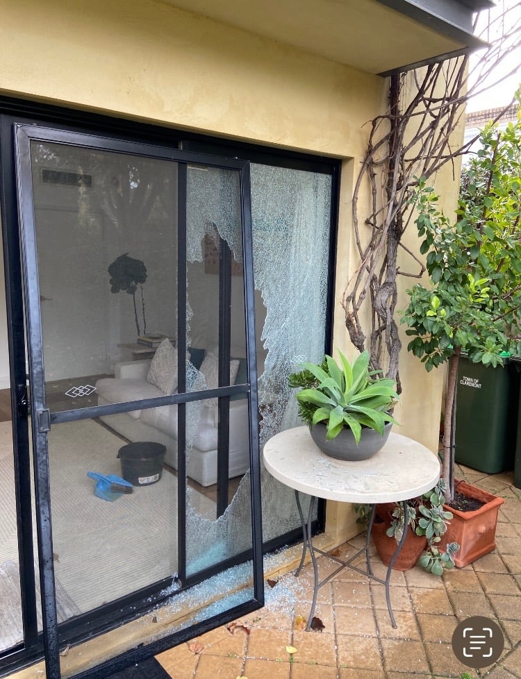 Smashed glass panel in a black-framed sliding door before repair